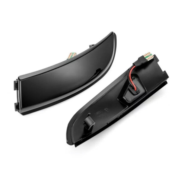Two sleek, curved black car light covers rest side by side; one shows a red wire inside, set against a plain white background.