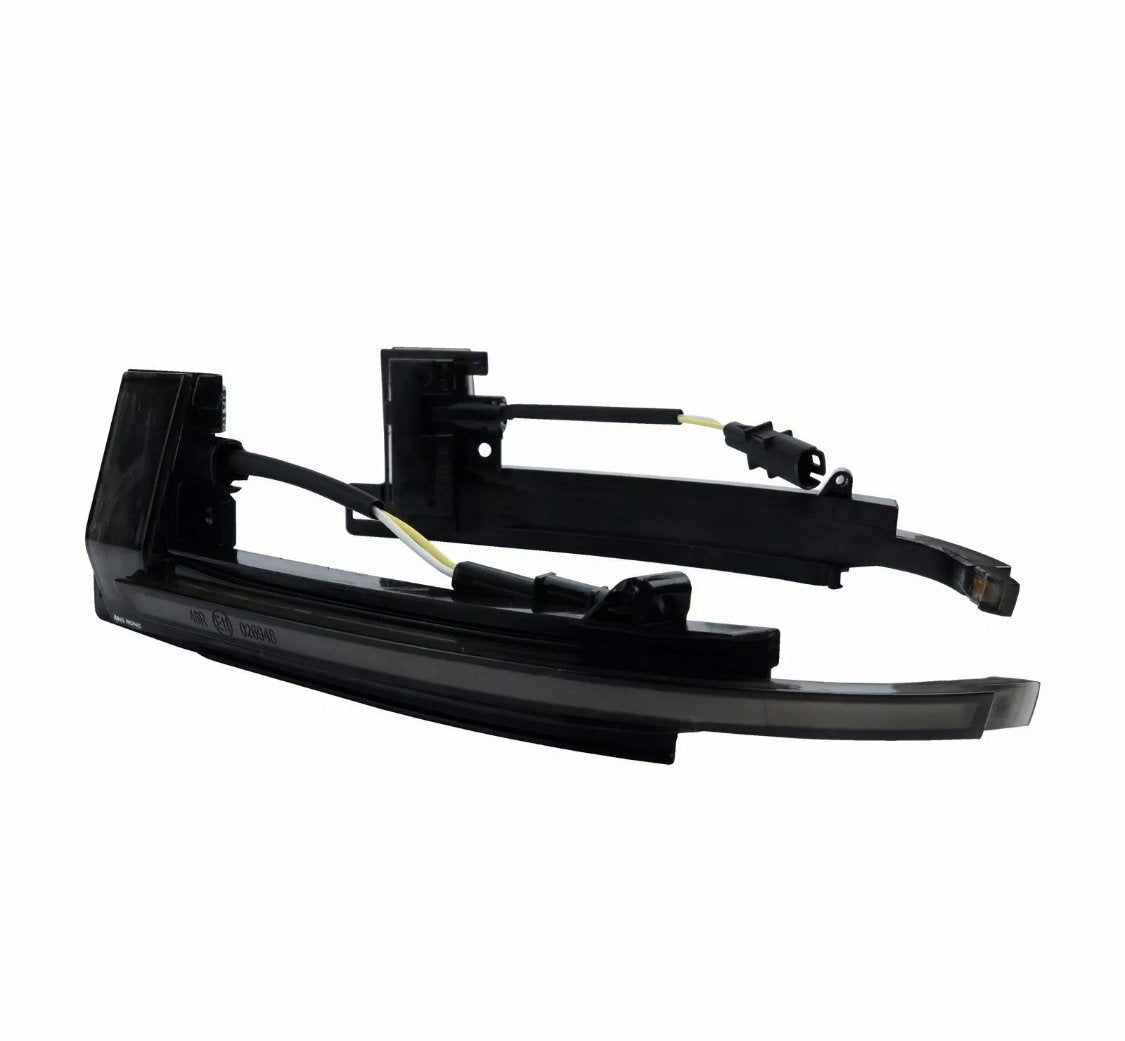 Black automotive side mirror turn signal lights are resting on a plain white background. They have curved shapes with attached wires, featuring a sleek, modern design suitable for vehicle integration.