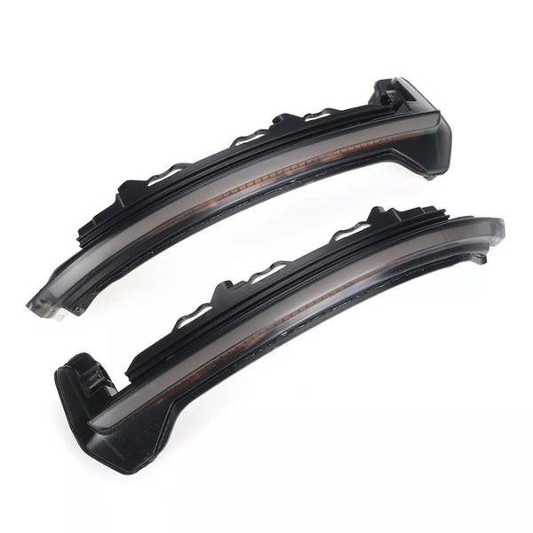Two sleek black curved LED car lights with translucent covers lie side by side on a white background, showcasing their modern design intended for automotive use.