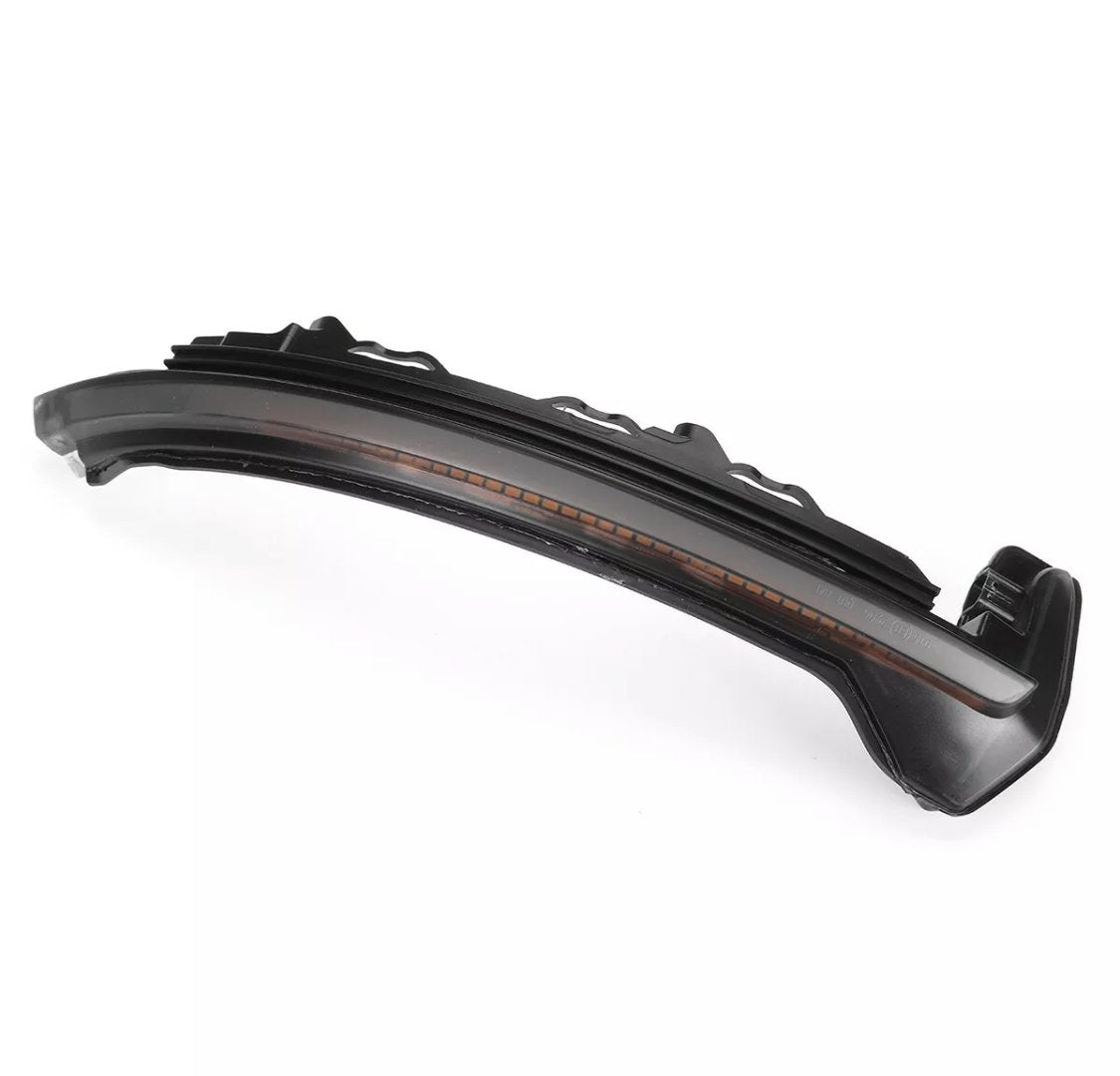 Curved black plastic car part with amber lens detail, likely a turn signal light, on a white background.