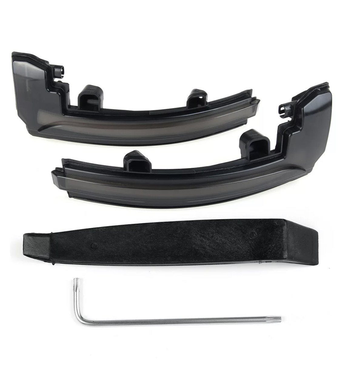 Two black plastic car light cover pieces rest on a white surface, accompanied by a black mounting bracket and a silver L-shaped tool beneath them.