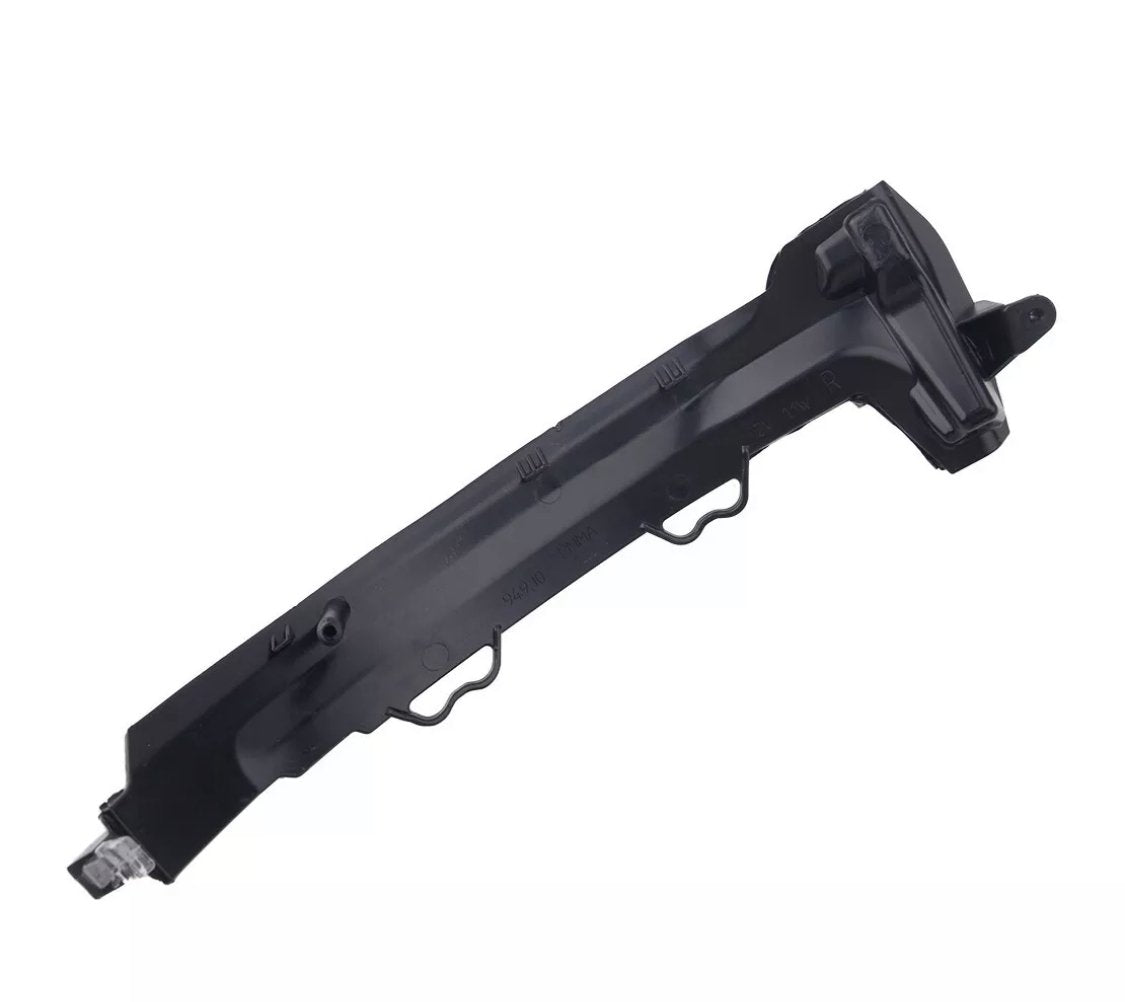 A black, angular plastic car component with multiple ridges and mounting points, possibly a bumper bracket, rests against a plain, white background.