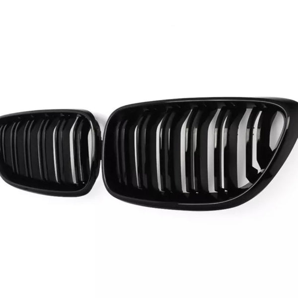 A pair of shiny, black car grilles with vertical slats are displayed against a plain white background, emphasizing their sleek, modern design.