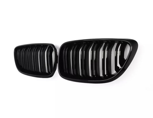 A pair of shiny, black car grilles with vertical slats are displayed against a plain white background, emphasizing their sleek, modern design.