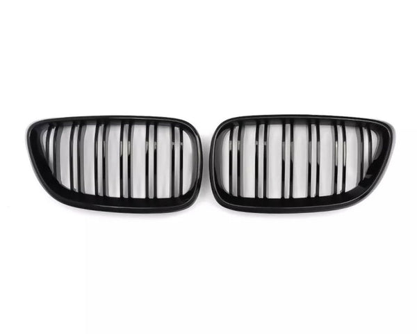Two black kidney-shaped car grilles with vertical slats, positioned side by side against a plain white background.