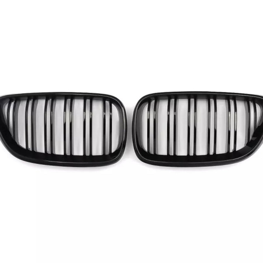 Two black kidney-shaped car grilles with vertical slats, positioned side by side against a plain white background.