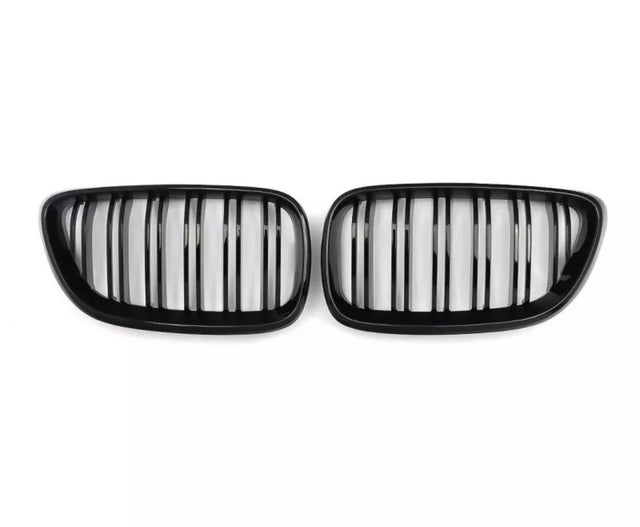 Two black kidney-shaped car grilles with vertical slats, positioned side by side against a plain white background.