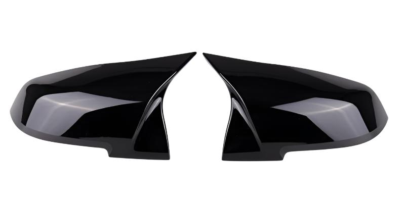 Two black, glossy side mirror covers are positioned symmetrically, facing each other against a plain white background.