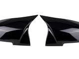 Two glossy black, aerodynamic mirror covers are displayed, positioned symmetrically facing each other, against a plain white background.