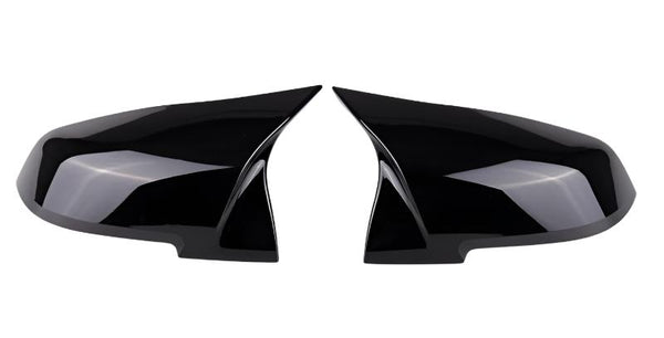 Two glossy black side mirror covers are positioned facing each other. They are streamlined, reflecting light subtly, against a plain white background.
