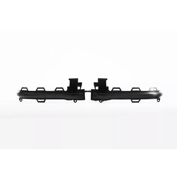 Black, rectangular plastic parts with hooks and protrusions lay side-by-side on a white background, appearing to be components of a larger assembly piece.