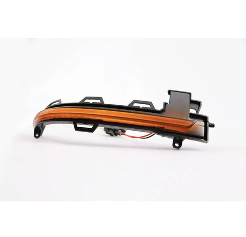 A curved, orange automotive light fixture with connectors sits on a white surface, accompanied by visible wires extending from its base.