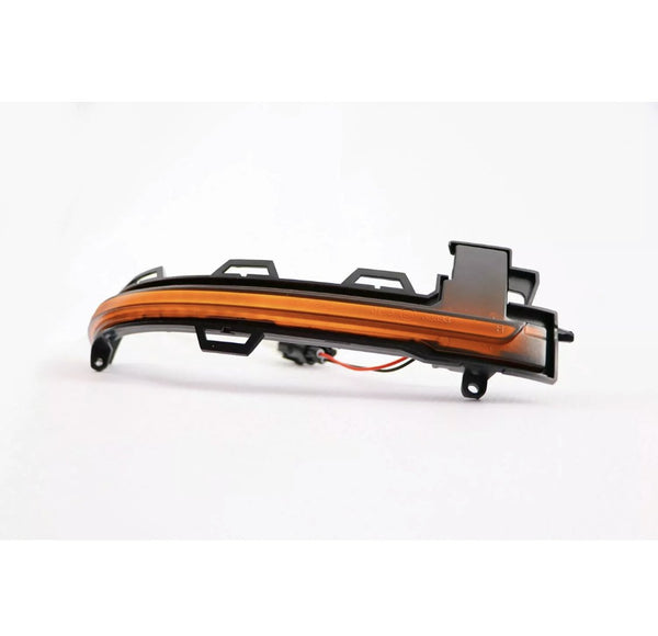 A curved, amber-colored car indicator light with plastic mounting brackets rests on a white background, featuring attached wiring for electrical connection.