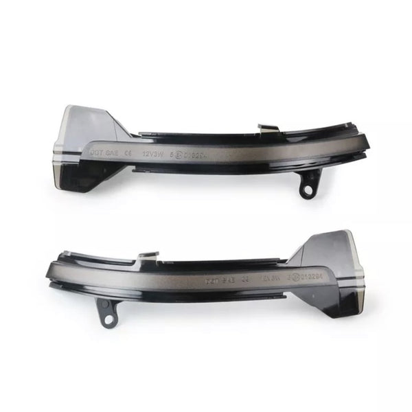 Two black plastic car components are positioned horizontally. Each piece has notches and extends outward with rounded edges. Text on them reads: "DOT SAE L 12V3W E1 012824" against a white background.