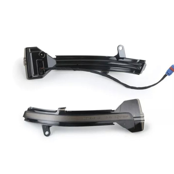 Black plastic automotive parts with connectors are placed on a white background. One piece has a wire ending in a blue and red plug.