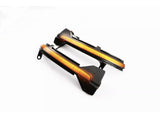Two black car side mirrors with integrated amber LED indicator strips, placed on a white background. They exhibit sleek, angular design elements typical of modern automotive components.
