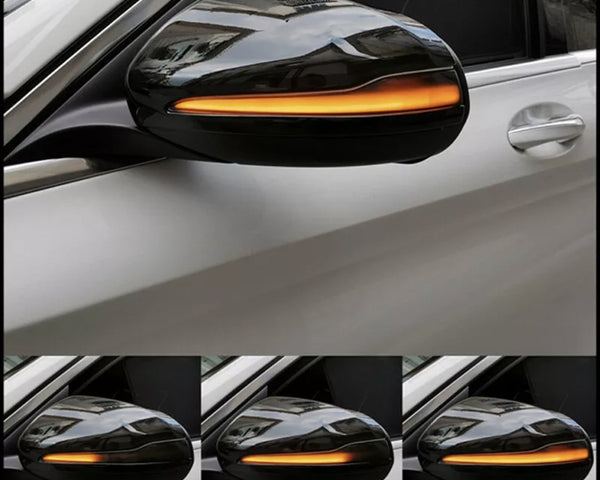A car's side mirror with an integrated amber light blinking sequentially, mounted on a white vehicle, shown in multiple frames captured from the side.