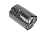 A cylindrical carbon fiber car exhaust tip with a metallic interior sits on a plain white background, featuring a small, central mounting screw.