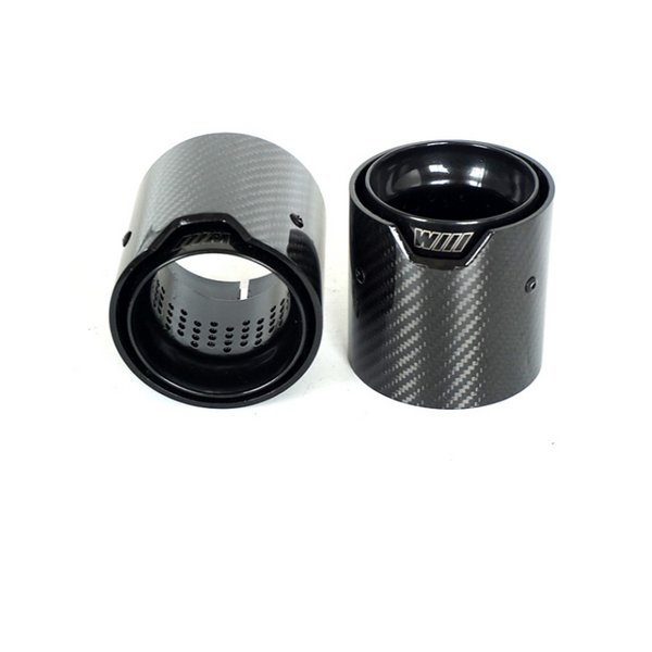 Two carbon fiber exhaust tips stand upright, showing a sleek, textured finish and internal perforations. "M" and "WILL" engravings are visible, likely in a product display setting.