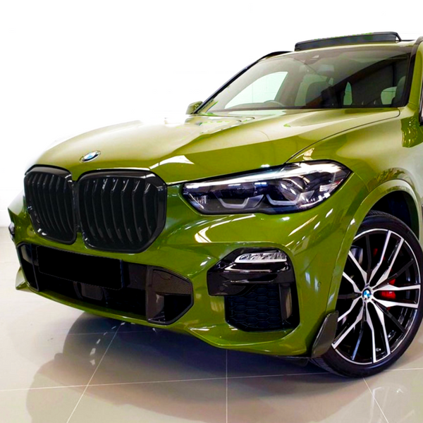 Green SUV parked indoors, displaying black grille, sharp headlights, and stylish alloy wheels. The setting is minimalistic, highlighting the vehicle's sleek design and shiny finish.