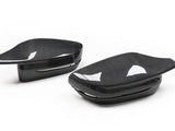 Two carbon fiber side mirror covers rest on a white background, showcasing a sleek, glossy finish with a subtle, woven pattern and reflection details.