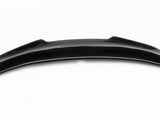 A sleek, black carbon fiber car spoiler with a curved, aerodynamic design rests against a plain white background.