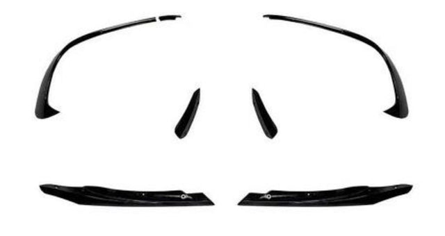 Black, glossy car spoilers and side skirts are arranged symmetrically on a white background, suggesting their use for a vehicle's aerodynamic enhancement.