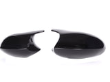 Two glossy black car side mirrors, positioned facing each other, rest against a plain white background.