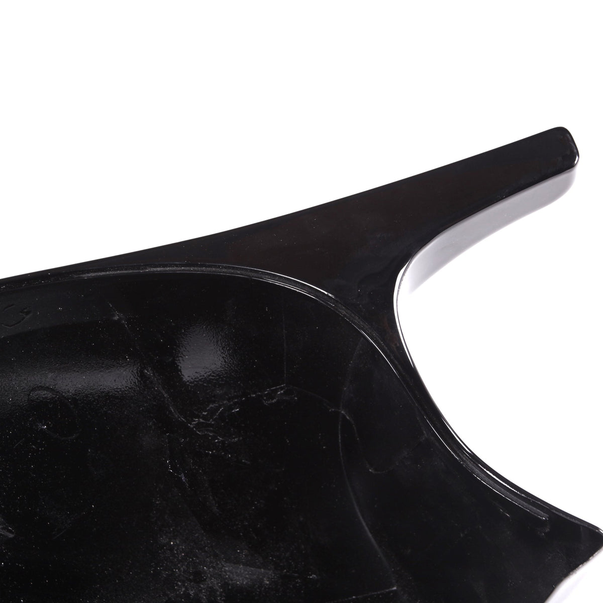 A glossy, black plastic object with a curved surface and a protruding handle, set against a white background.