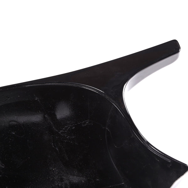A glossy, black plastic object with a curved surface and a protruding handle, set against a white background.