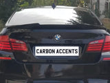 Car parked on a road, showcasing its rear with red taillights, a BMW emblem, and a license plate reading 