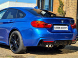 A blue BMW car is parked, showcasing its rear design and dual exhausts. The license plate reads 