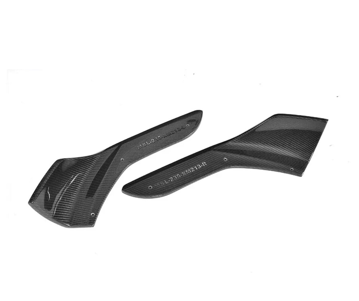 Two carbon fiber car parts lie side by side, textured with a glossy finish, against a plain white background. Visible text reads "ALS.2.45.PN23.4.R" on each piece.