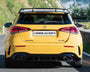 A yellow Mercedes-Benz A 35 is parked on a mountain road. It has a spoiler and visible dual exhausts. The license plate reads "CARBON ACCENTS." Lush greenery surrounds the area.