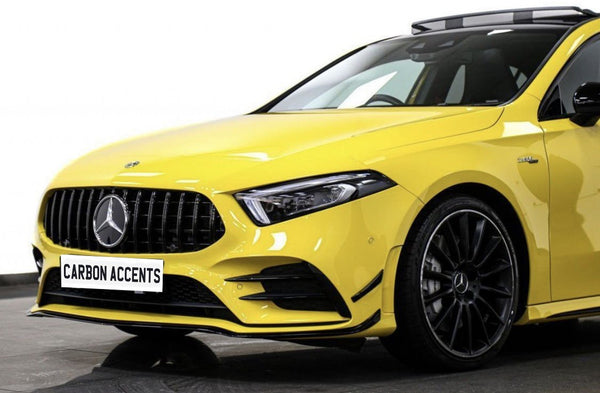 Yellow luxury car with a prominent logo is parked on a showroom floor. The license plate reads "CARBON ACCENTS." The car features sleek black wheels and a modern design.